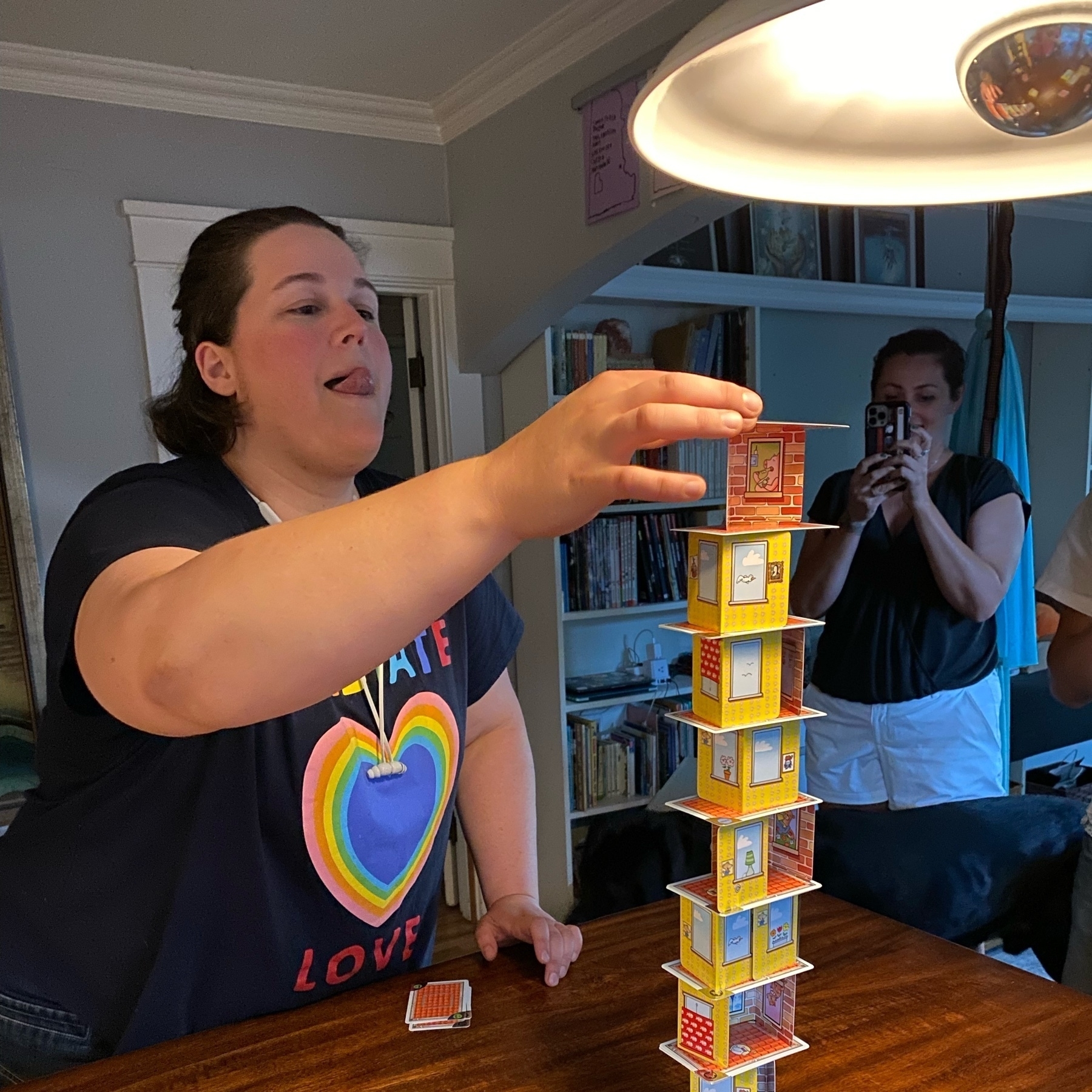 Laura successfully adding a structure card to a high, wobbly Rhino Hero tower! 