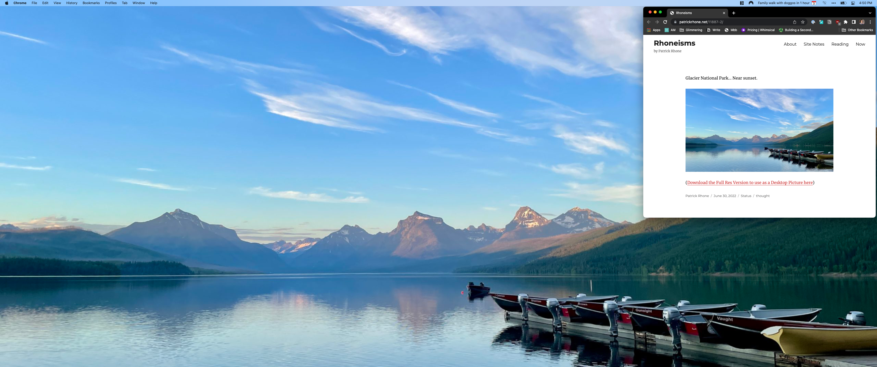 Galcier National Park Near sunset by Patrick Rhone. Wide angle photo  of a dock lined with colorful boats going out to the lake with green hills and snowcapped mountain range in the background.