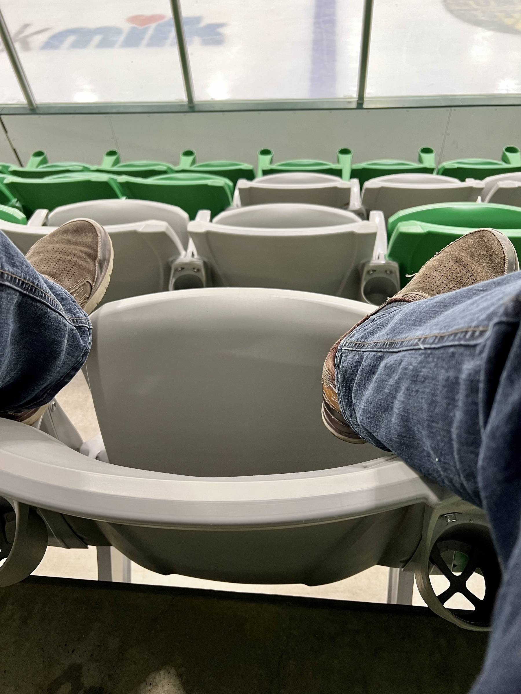 My feet up on the seat in front of me in a hockey rink. 