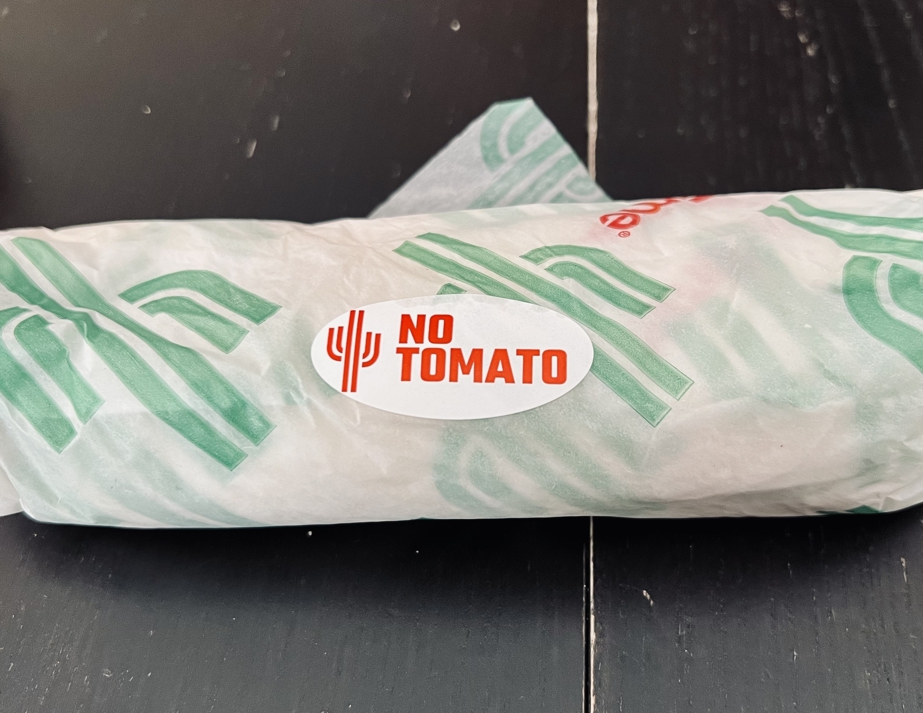 A burrito with a “no tomato” sticker on it. 