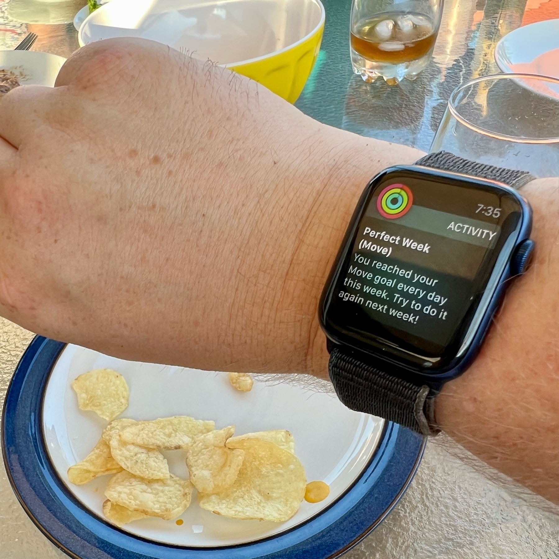 A picture of my Apple Watch telling me I had a perfect move week closing all my move rings this week with a plate of chips in the background. 