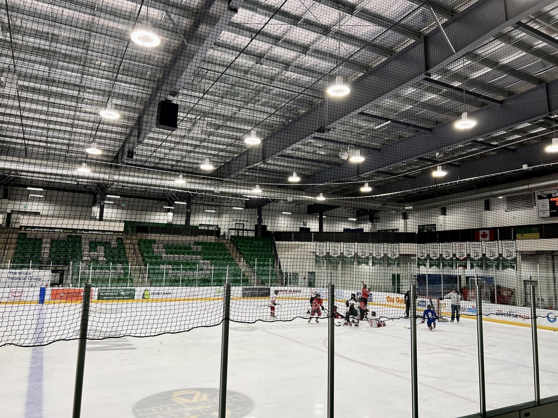 A kid’s hockey team practicing on the ice in an otherwise empty rink. 