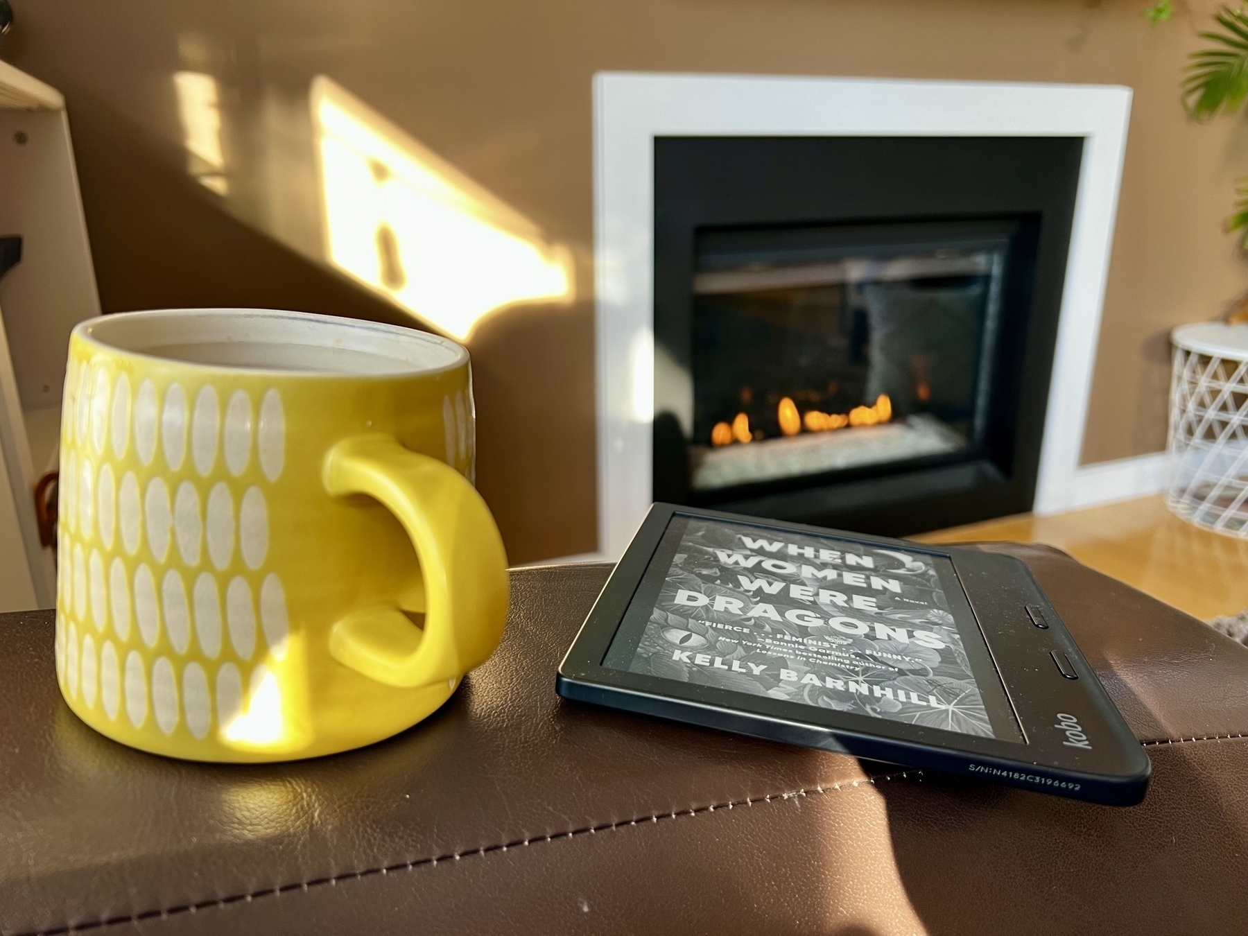 A coffee mug sits next to a Kobo Libra 2 with the cover of “When Women Were Dragons” by Kelly Barnhill on its display. 