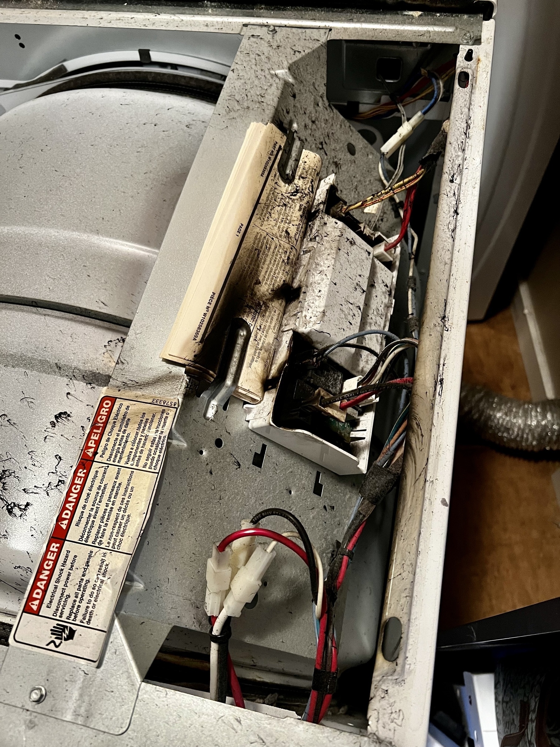 Image of the top of a clothes dryer with the top removed showing blackened circuit board area.