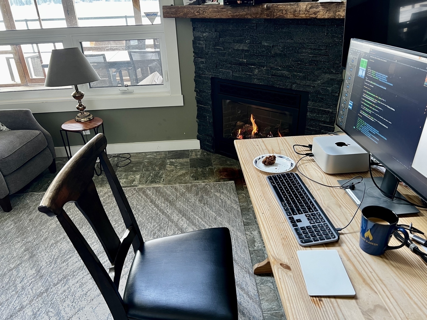 A Mac Studio hooked up to a monitor on a desk that is not my usual location in front of a fireplace. 