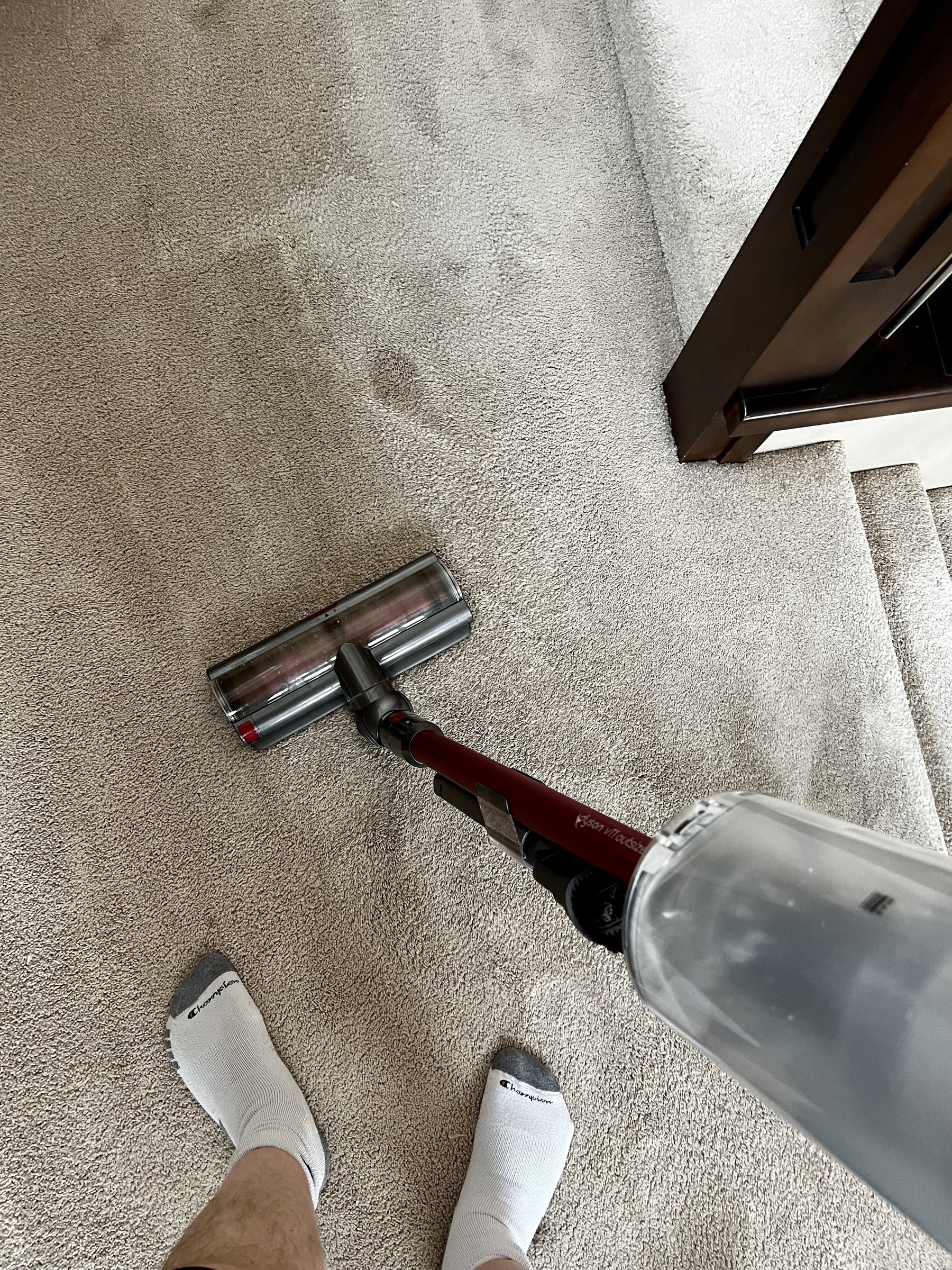 Looking down at a vacuum and some socked feet 