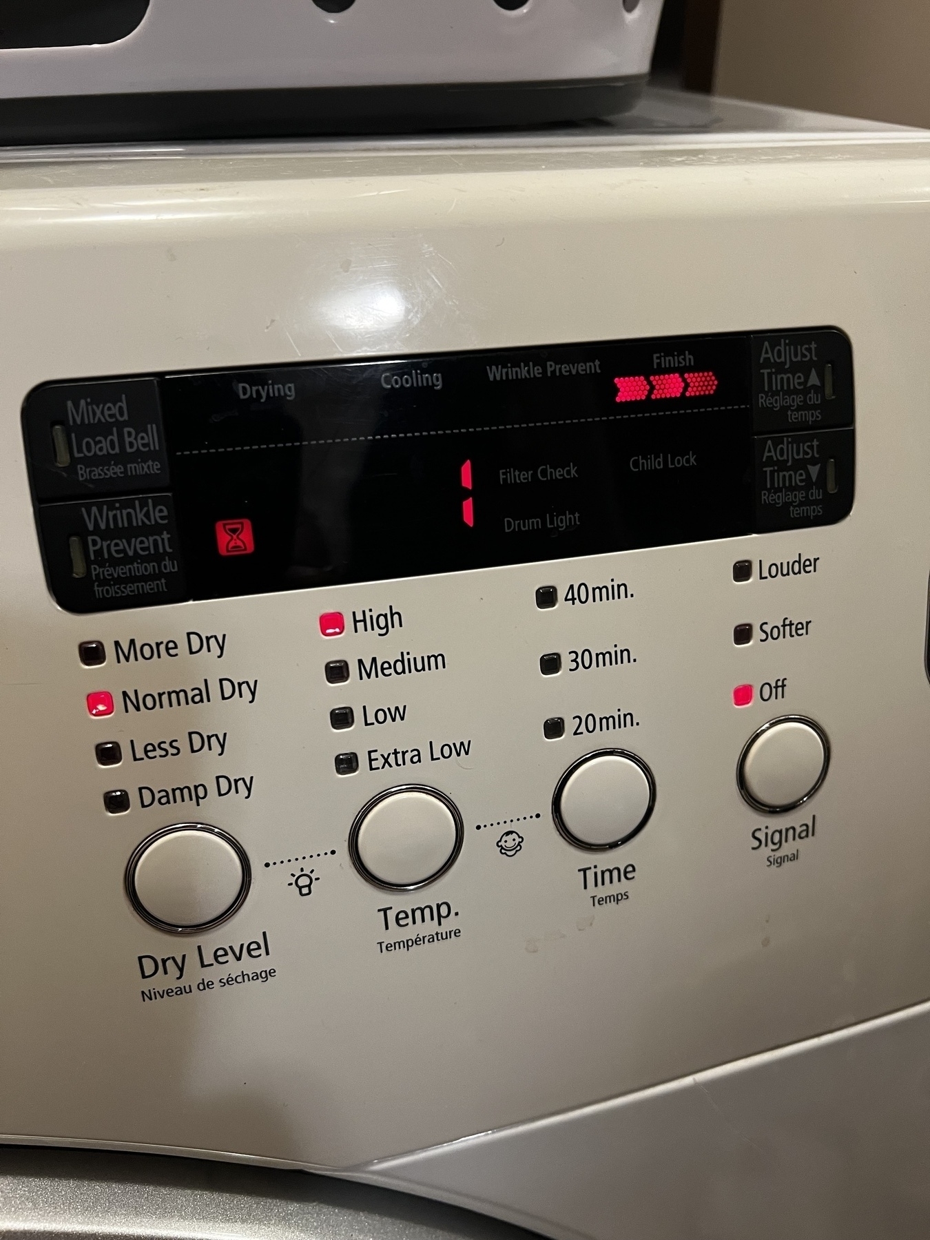 A washing machine control panel displays various settings, including drying levels, temperature, and signal options. The time remaining is “1”