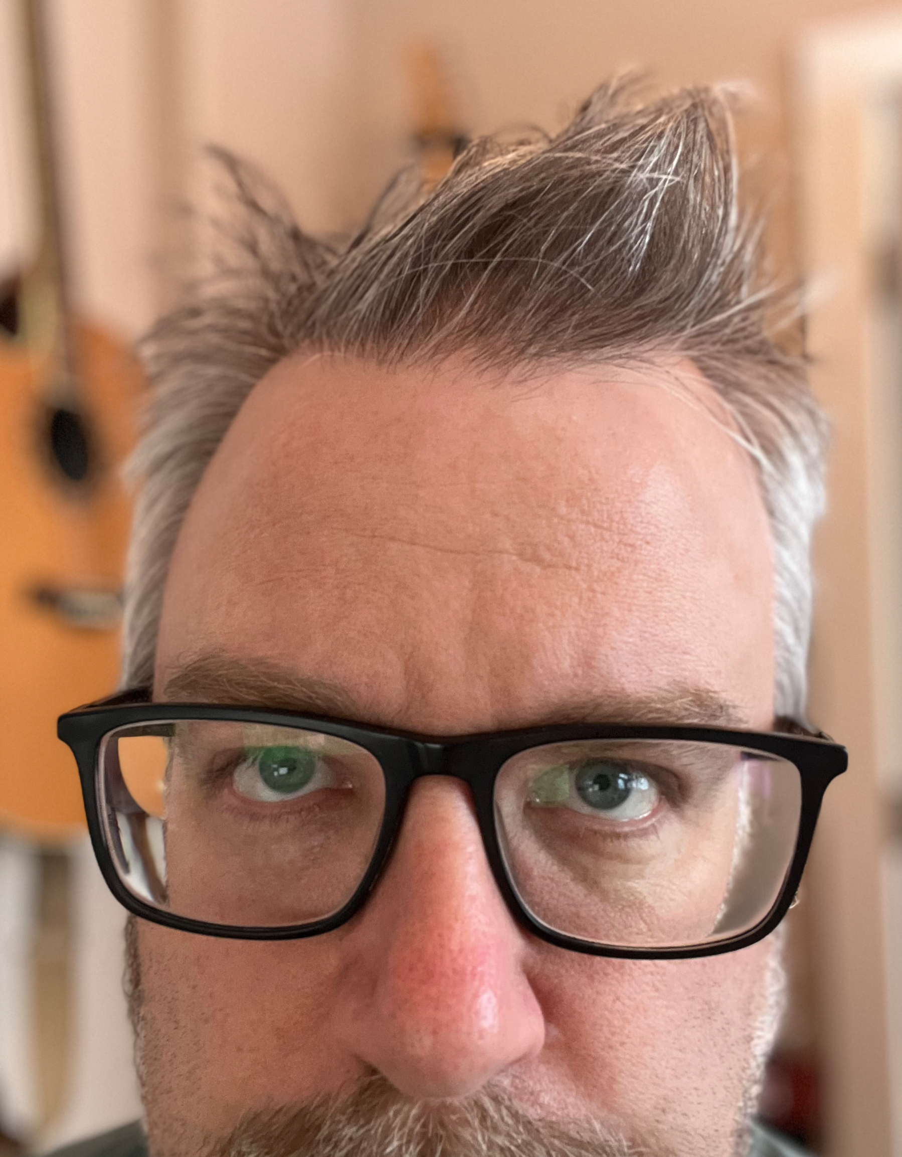 A person with glasses and spiky gray hair is looking directly at the camera.