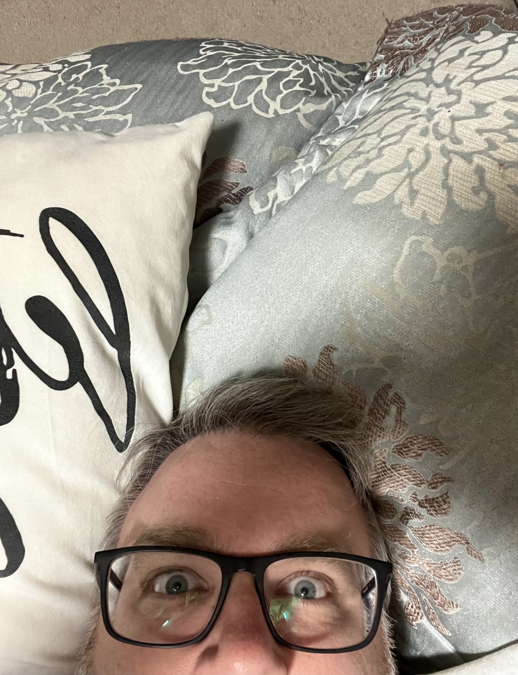 Selfie of the top half of my head looking tired and exasperated laying on a pillow. 
