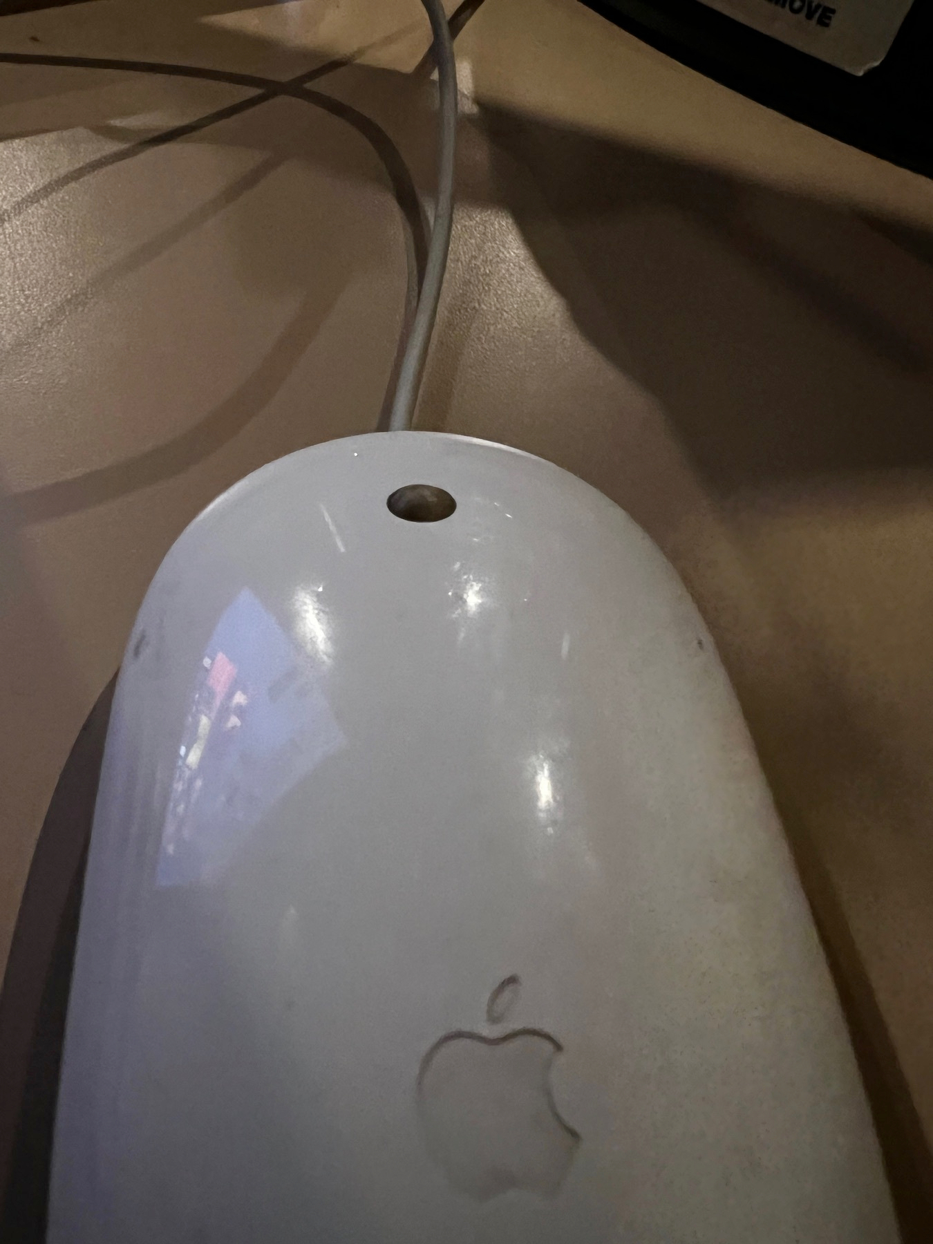A photo of a dirty Apple Mighty Mouse / Apple Mouse with a cord coming out the top of it.