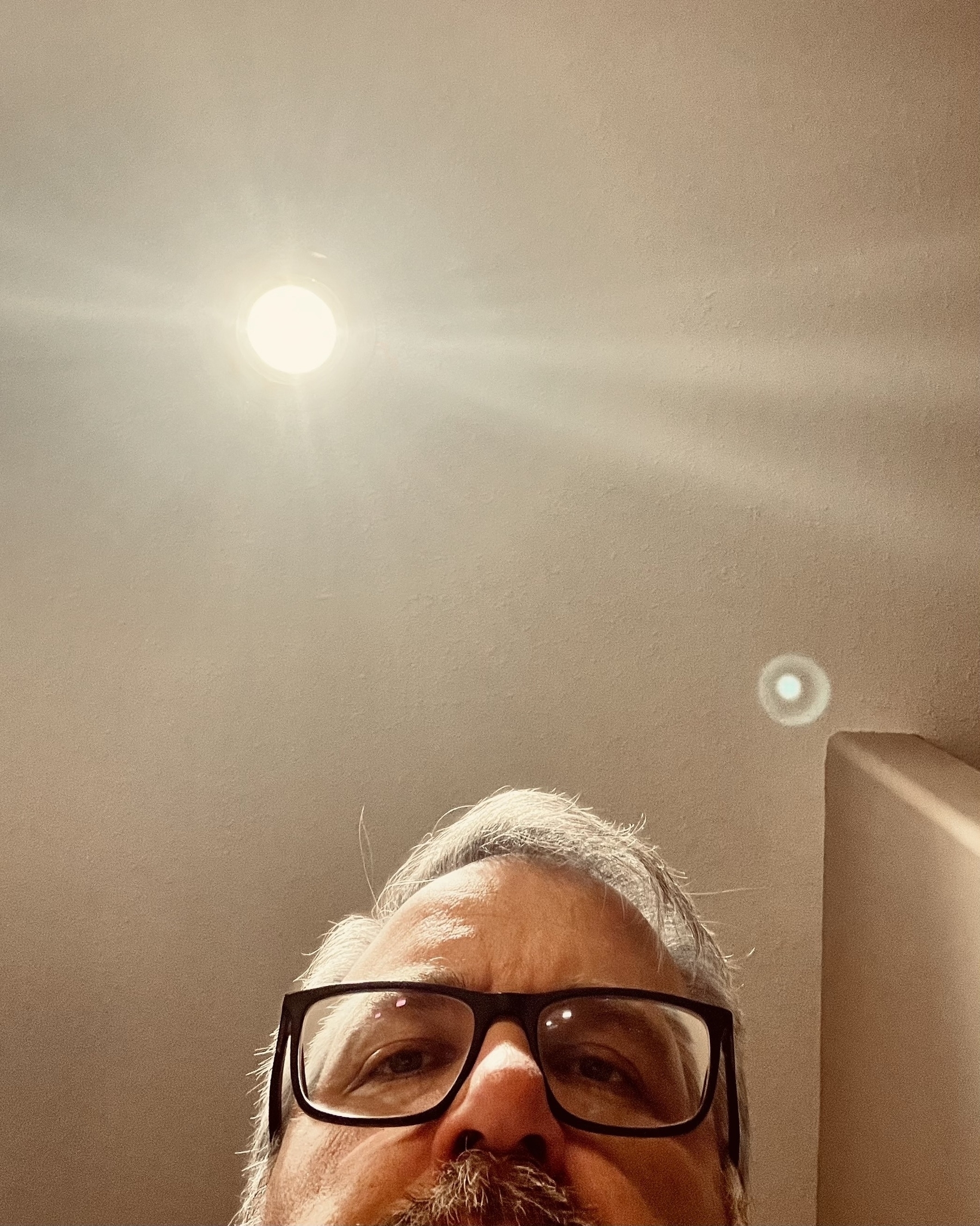 A person wearing glasses is partially visible under a ceiling light.