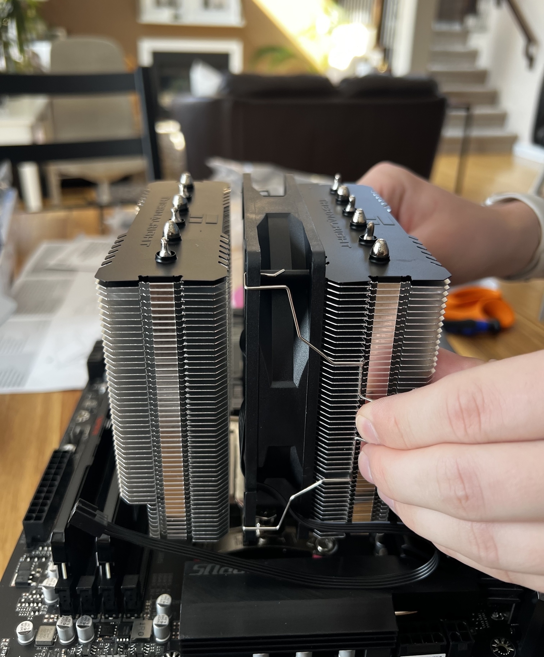 A closeup of a giant cpu fan and heat sink being put into place on a computer motherboard. 