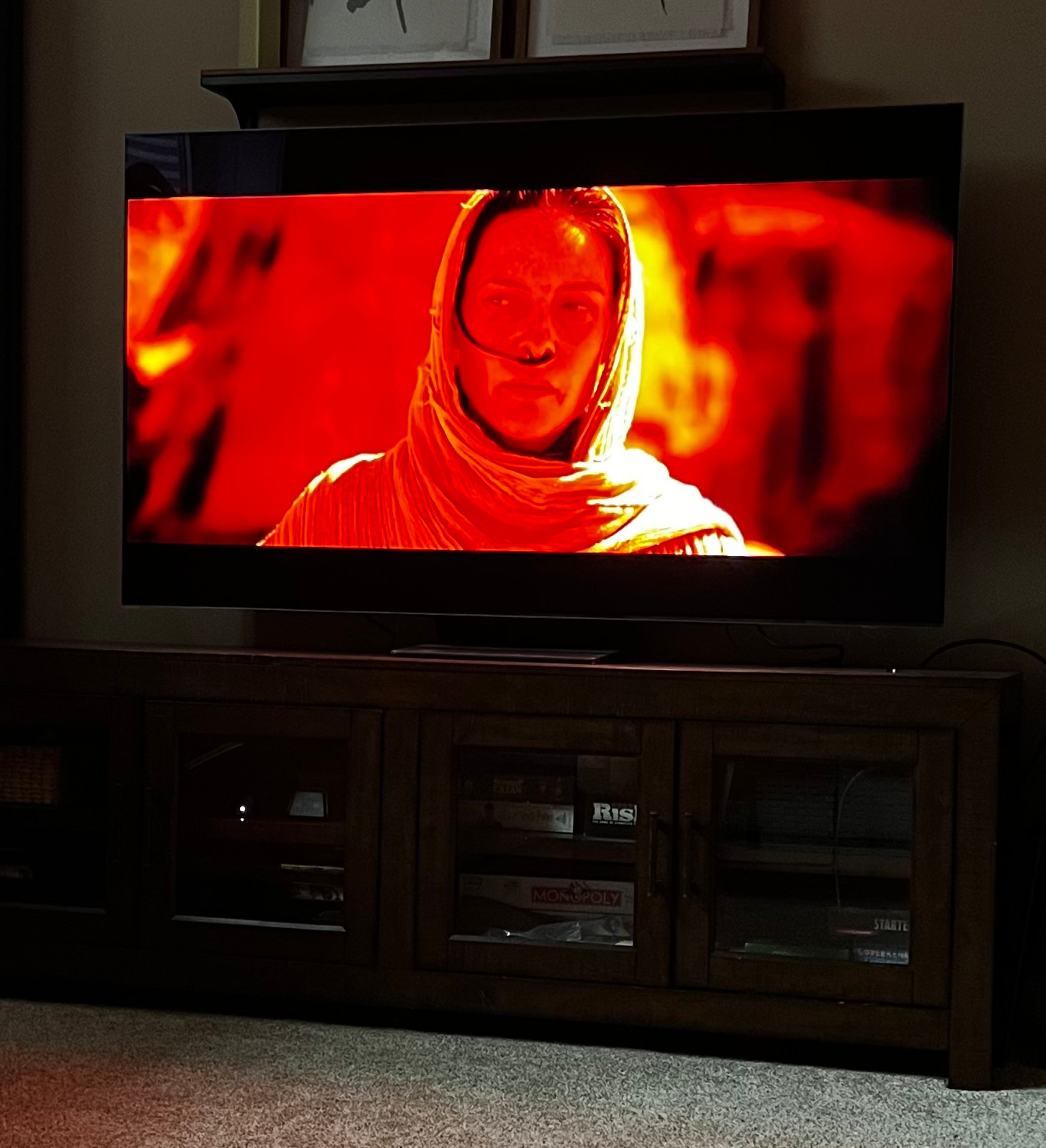 Rebecca Ferguson wearing a hooded garment is shown on a television screen with intense red and orange lighting. From the start of Dune 2