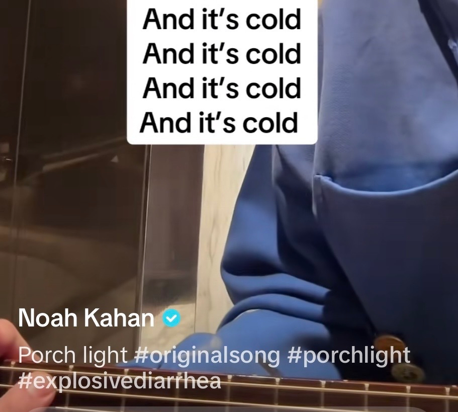 Noah Kahan in a blue shirt is holding a guitar while text repeats the phrase And it's cold. With hashtags at the bottom including #explosivediarrhea