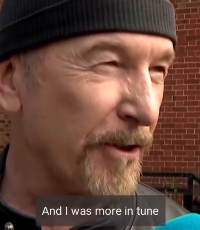 A man wearing a black beanie and a leather jacket is speaking, with the subtitle And I was more in tune displayed at the bottom.