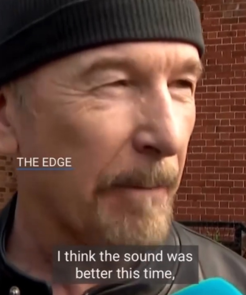A man wearing a black beanie and jacket is speaking in front of a brick wall with the name THE EDGE and the subtitle I think the sound was better this time, displayed on the screen.