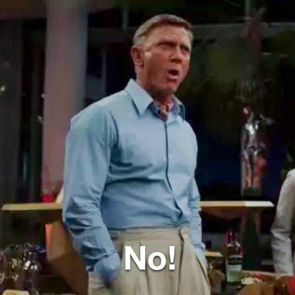 Daniel Craig as Benoit Blanc wearing a light blue shirt and beige pants is standing with one hand in his pocket, expressing surprise or refusal with the word No! displayed.