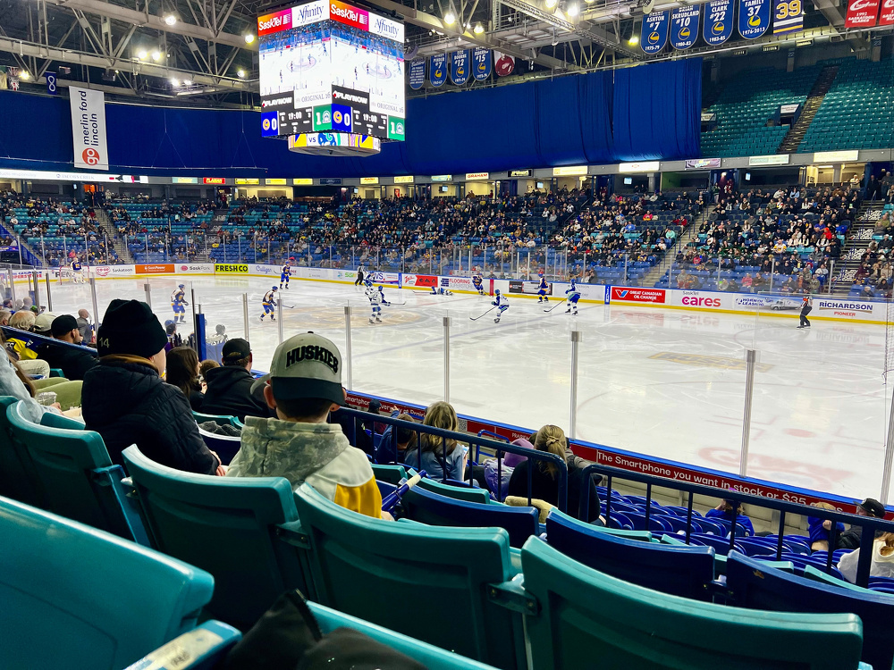A hockey game is taking place in an indoor arena with a crowd watching from the stands.
