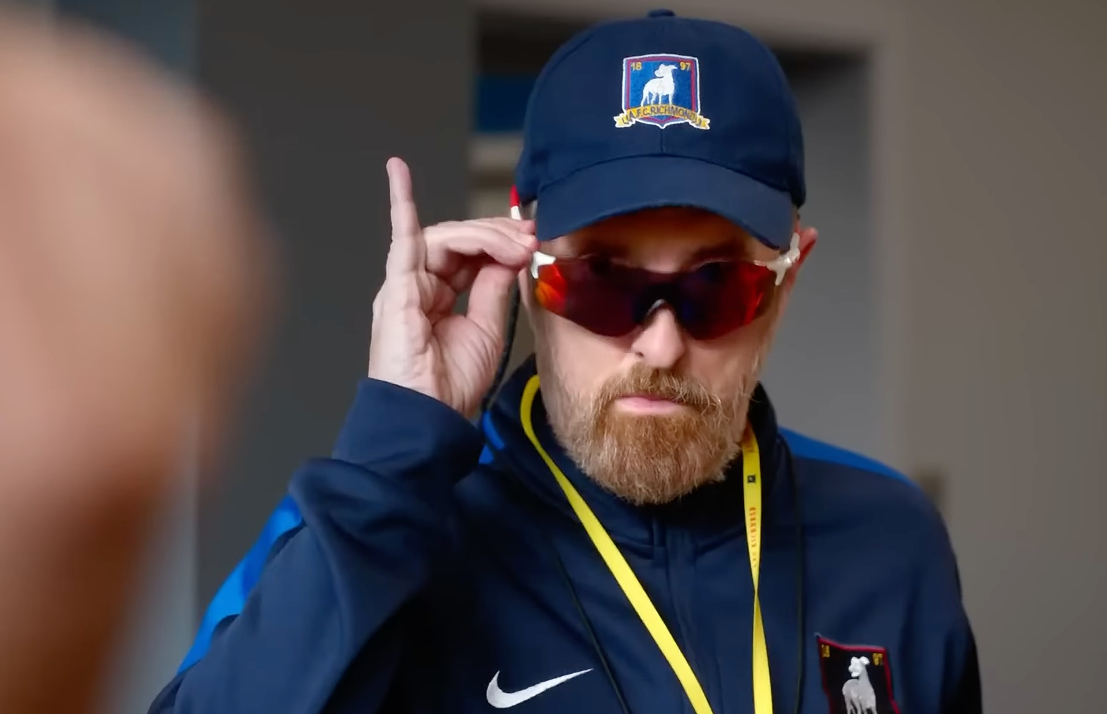 Coach Beard with sunglasses on checking out something.