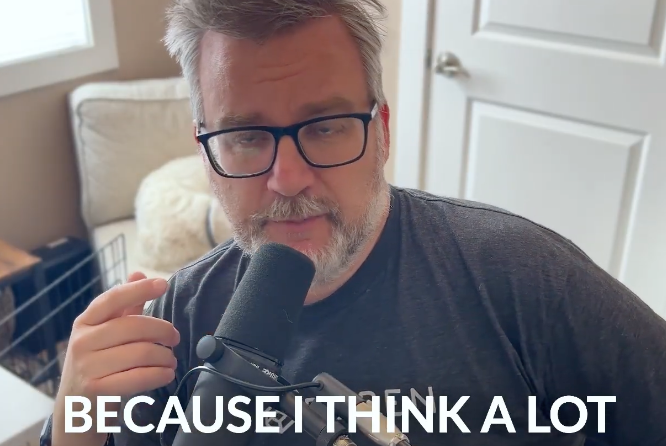 A person with glasses and a beard is speaking into a microphone with the text BECAUSE I THINK A LOT at the bottom.