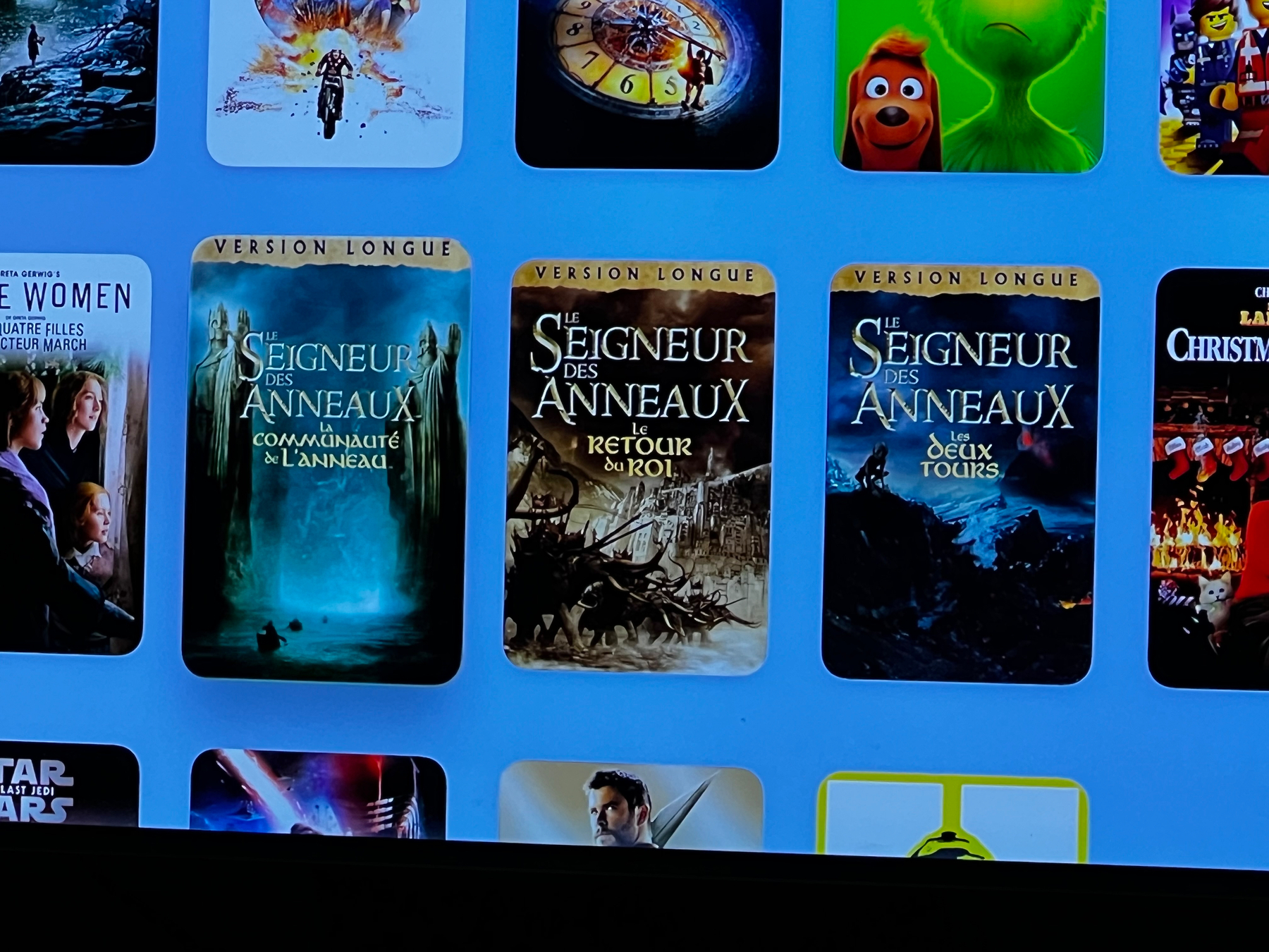 A selection of movies is displayed on a digital screen, including French versions of The Lord of the Rings series.