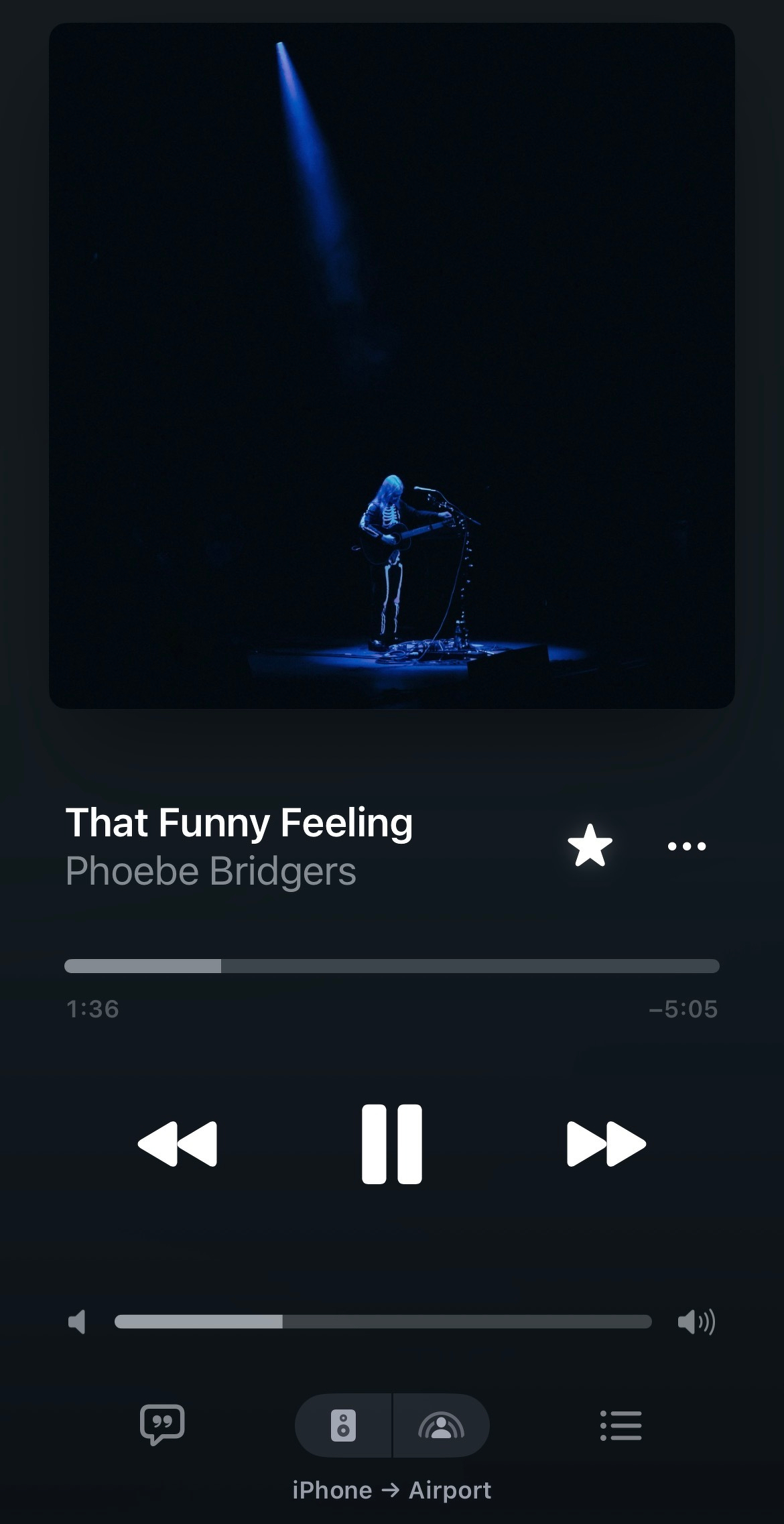 A music player screen shows the song That Funny Feeling by Phoebe Bridgers playing, with a dark, spotlight-lit stage image of a musician in the background.