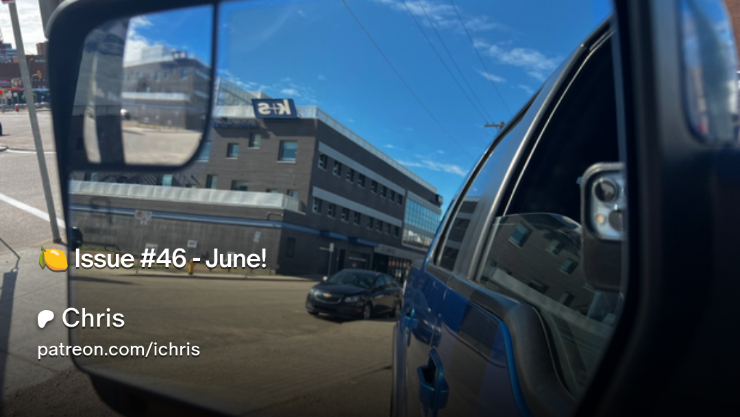 A side mirror reflection shows a street scene with buildings and a blue sky.