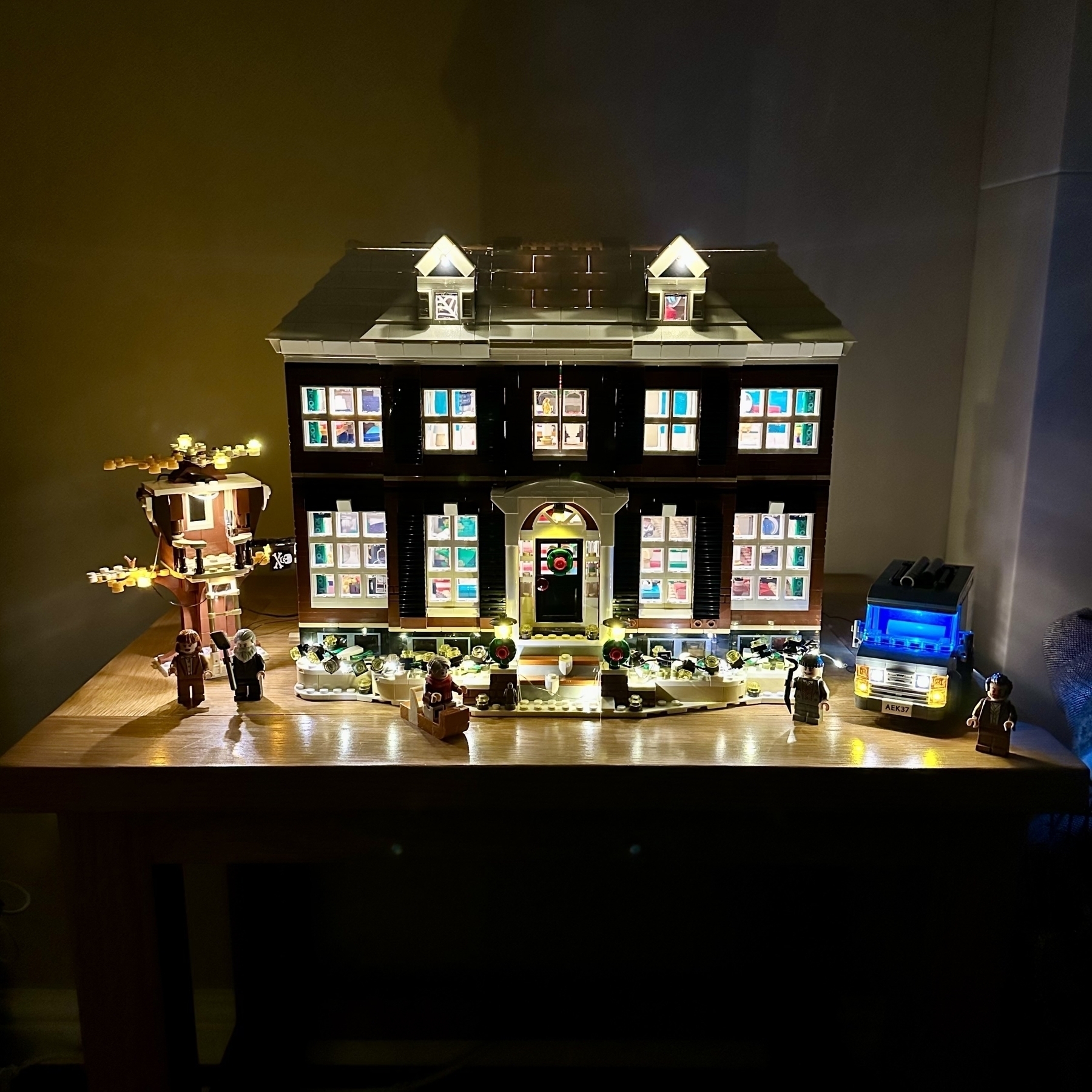The Home Alone Lego set illuminated on a small table.