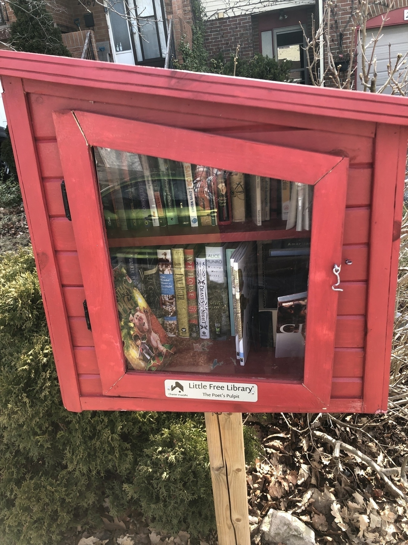 A red box on a wooden pole filled with books as part of a free library.  