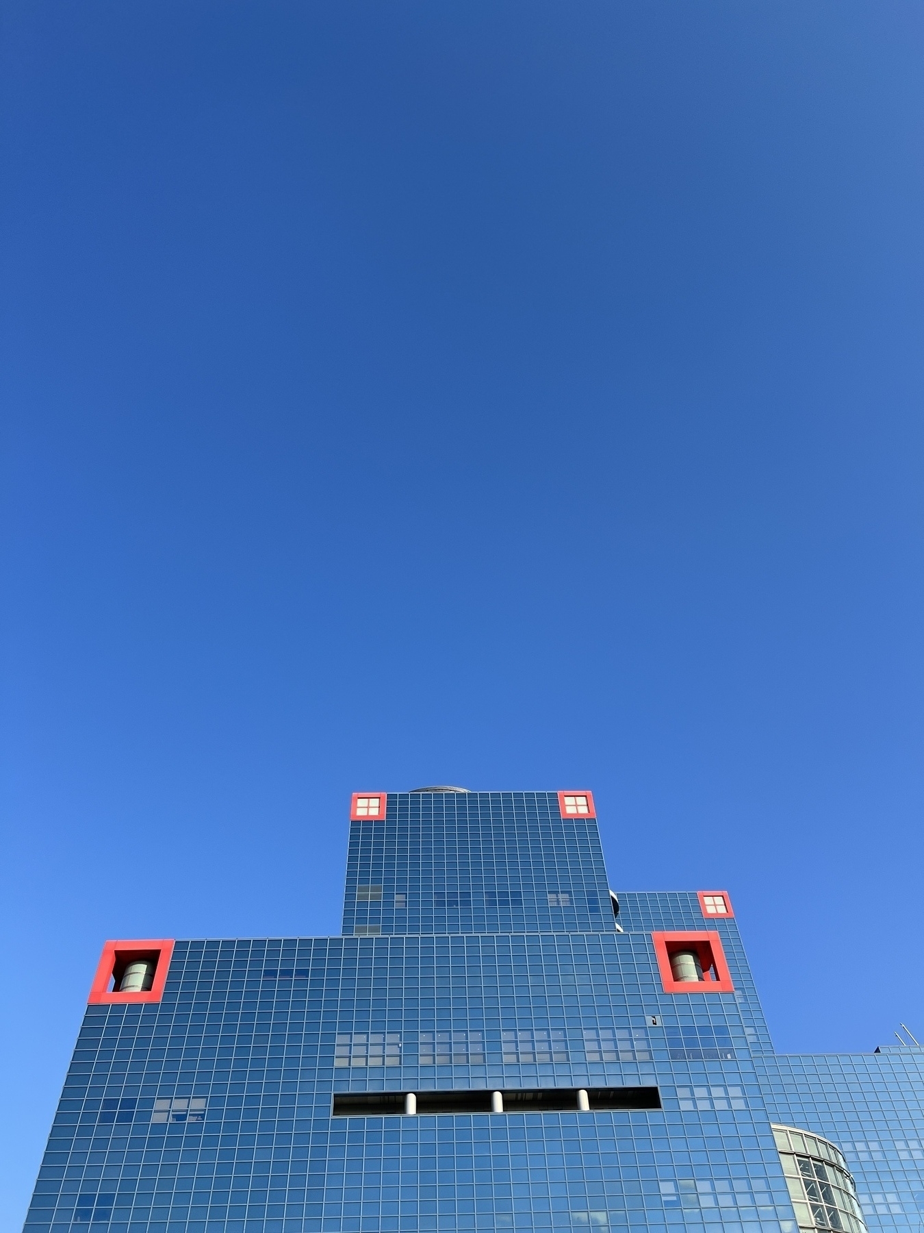 Building with blue windows nearly blending into the clear blue sky above