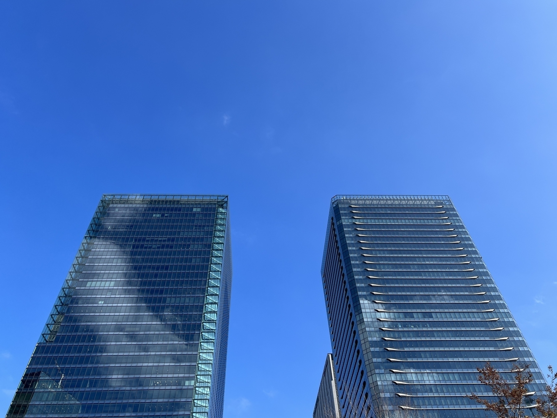 Looking up at two skyscrapers (the Osaka Front Buildings) and a blue sky