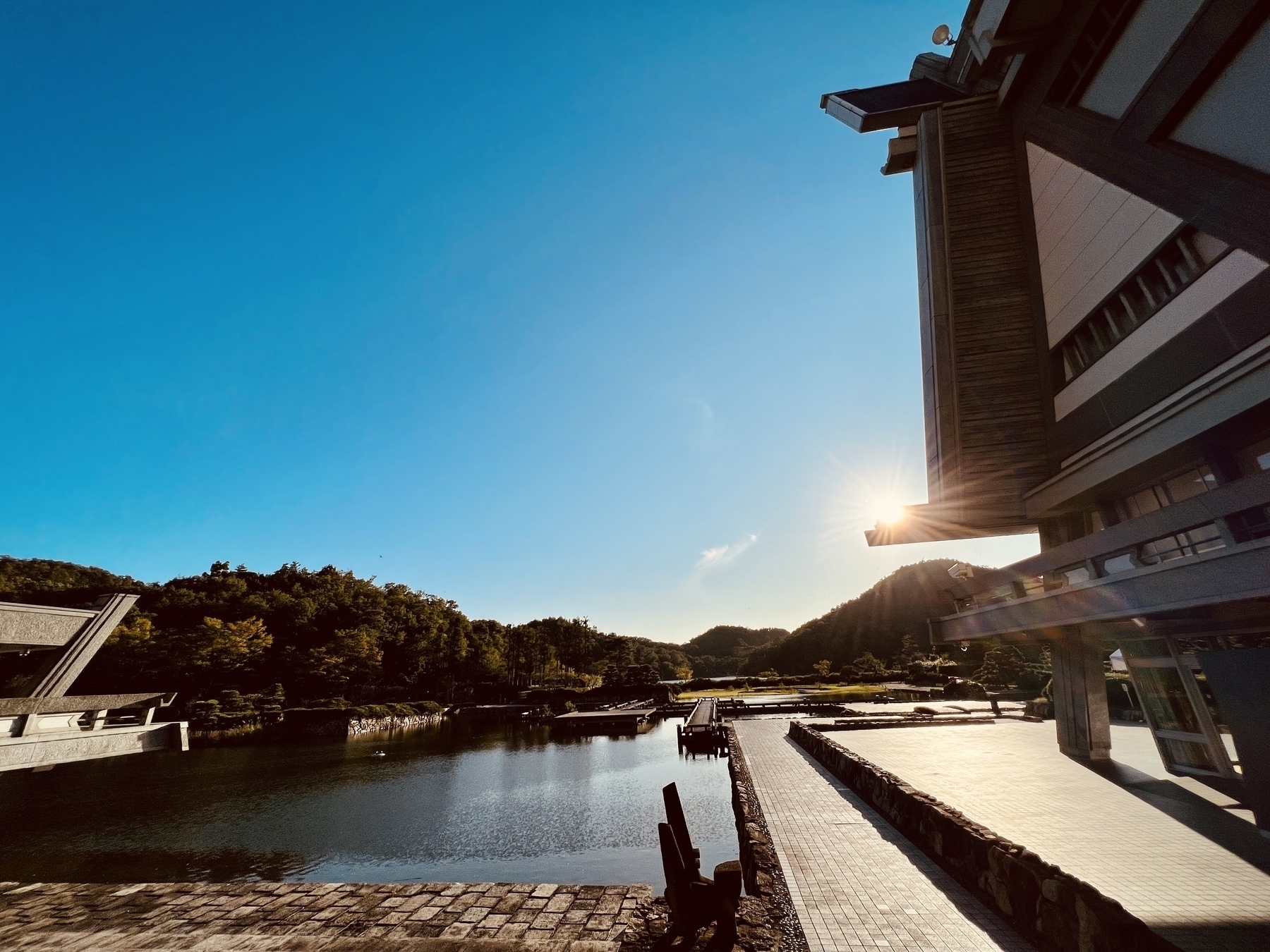 Sun goes low behind a part of the Kyoto International building next to the pond on a clear day