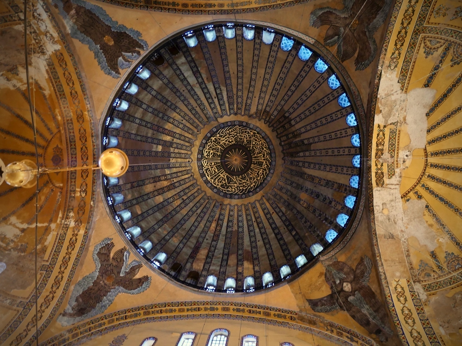 A nearly straight on shot of the underside of the main dome featuring Arabic writing, and surrounding are depictions of four angels