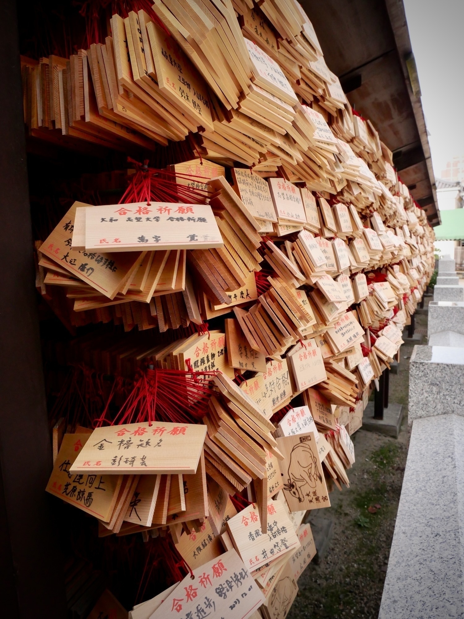 rows and rows of wooden prayer tablets. Shot taken from an oblique angle to show how many are stacked upon one another