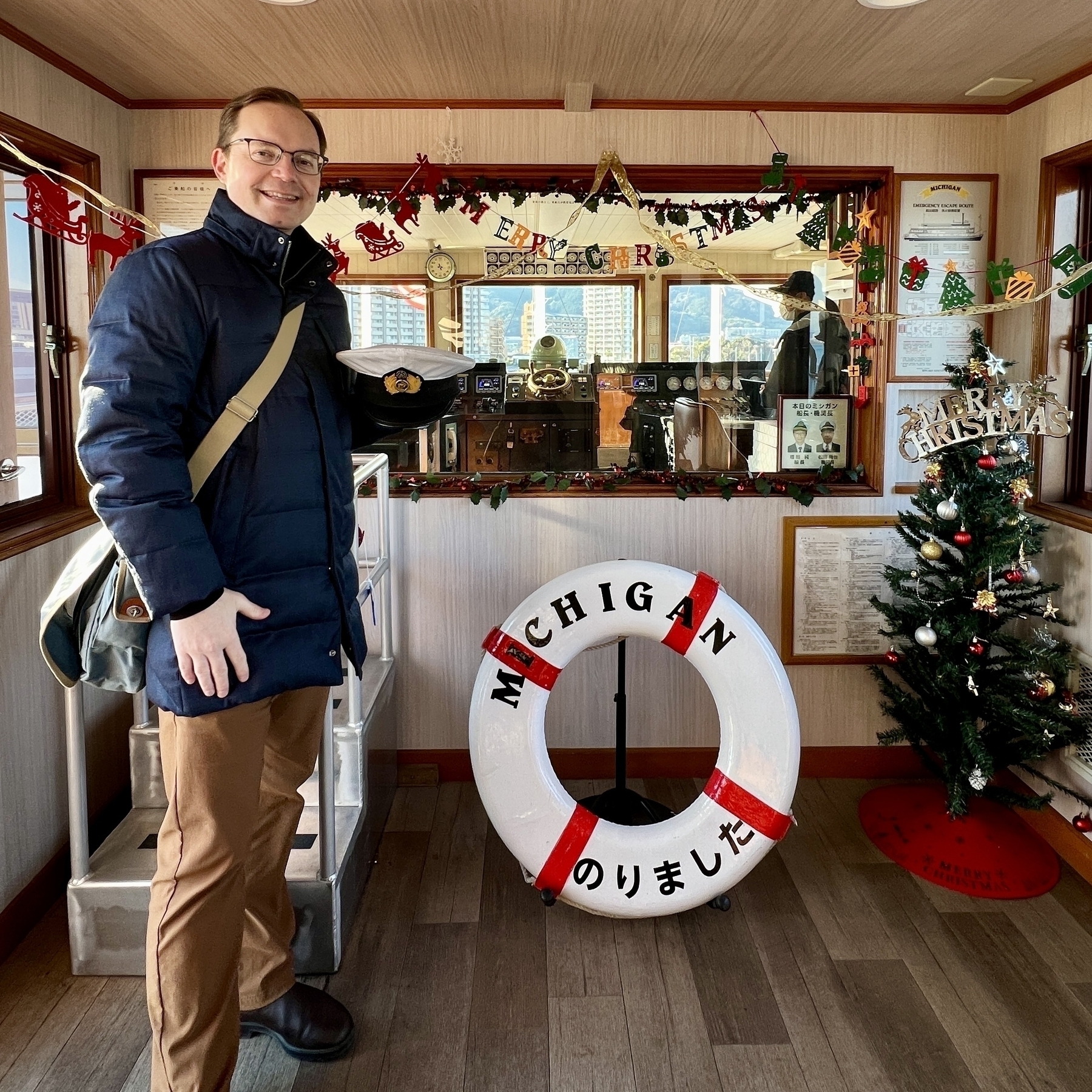 Chad poses in front of a window looking into the ship’s cabin. There is an Xmas tree to the right