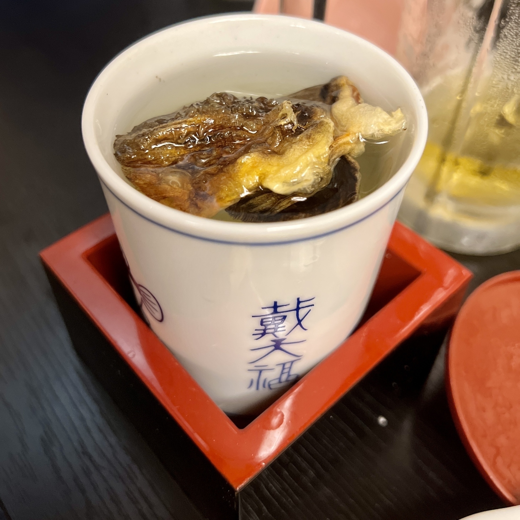 Cup of alcohol with pieces of fish floating at the top