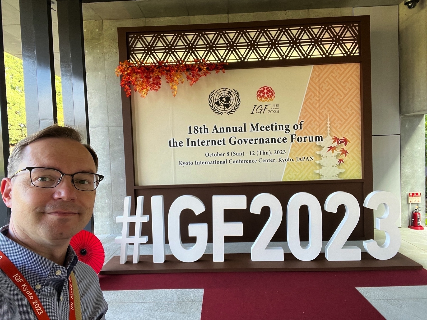 Chad takes a selfie at the entrance sign for the conference in front of a meter-tall novely #IGF2023 hashtag
