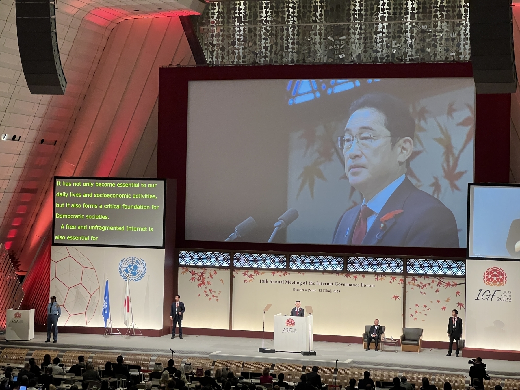 Japanese Prime Minister Kishida delivers a speech. The captions screen displays the lines:&10;&10;It has not only become essential to our daily lives and socioeconomic activities, but it also forms a critical foundation for Democratic societies.&10;A free and unfragmented Internet is also essential for… 