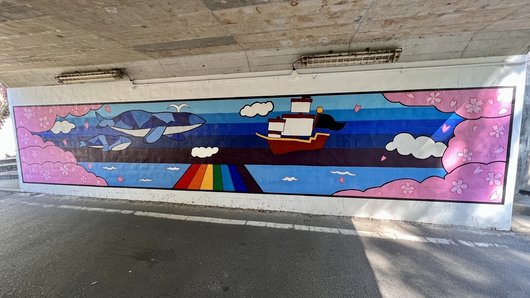 Wall mural depicting whales, a sailing ship, rainbows, and cherry blossoms