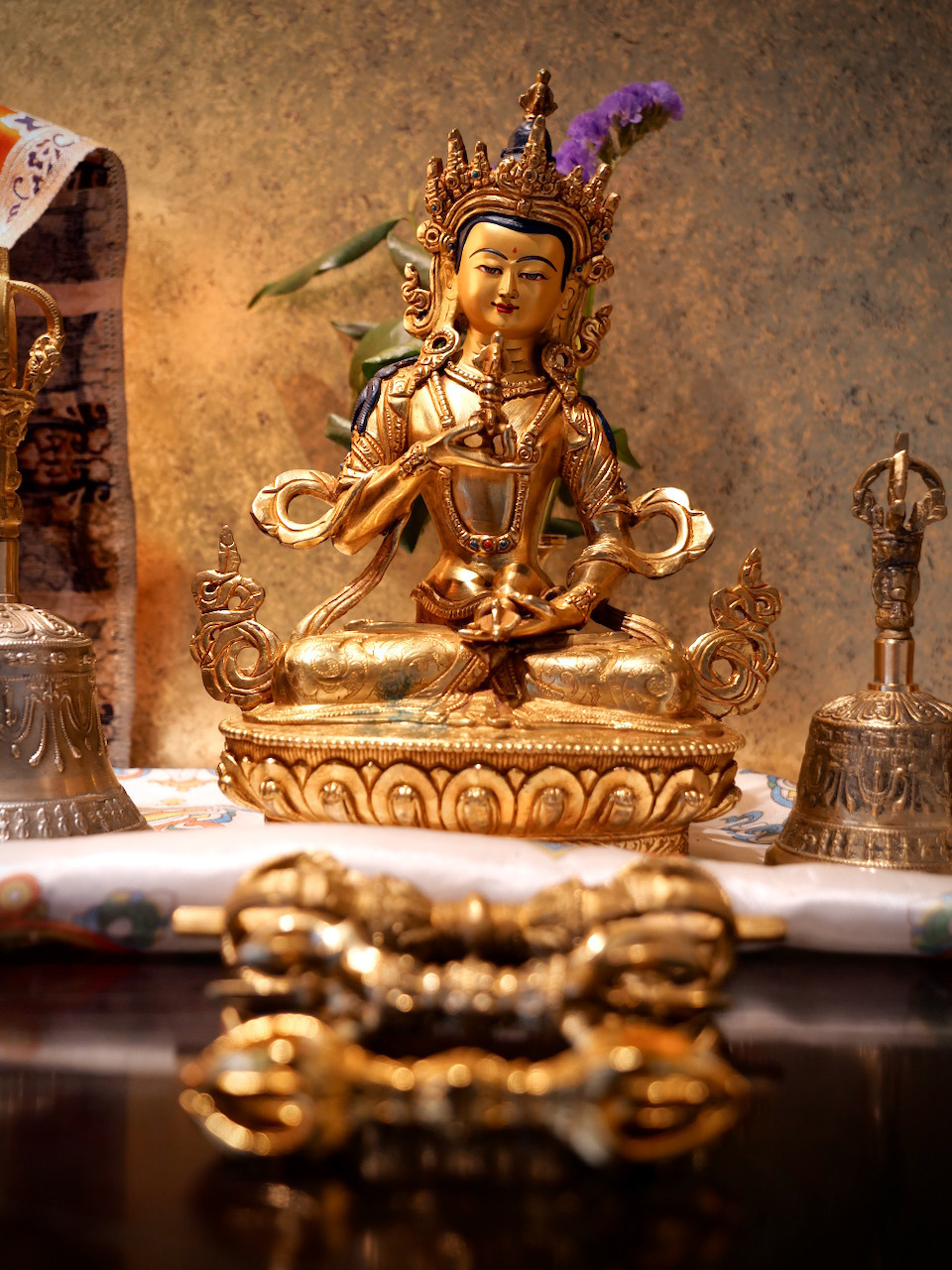 Small Tibetan Buddhist statue with three vajra sitting in front of the statue