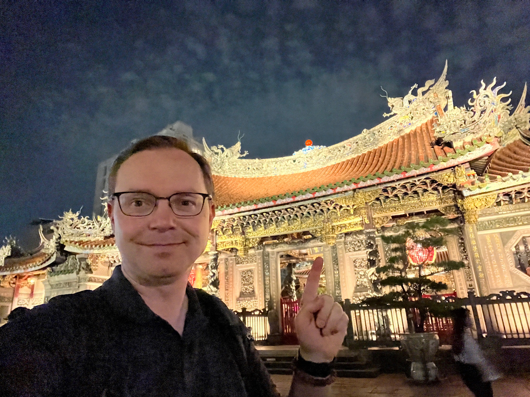 Chad selfie in front of of the lot up Lungshan Temple gates at night