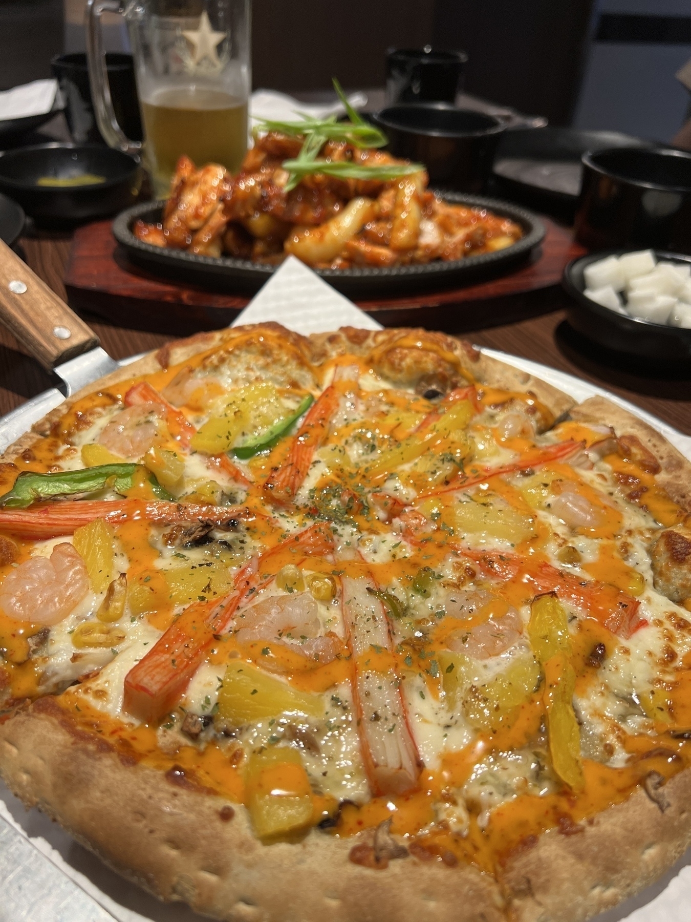 Seafood pizza with kamaboko on it! In the background is spicy Korean chicken