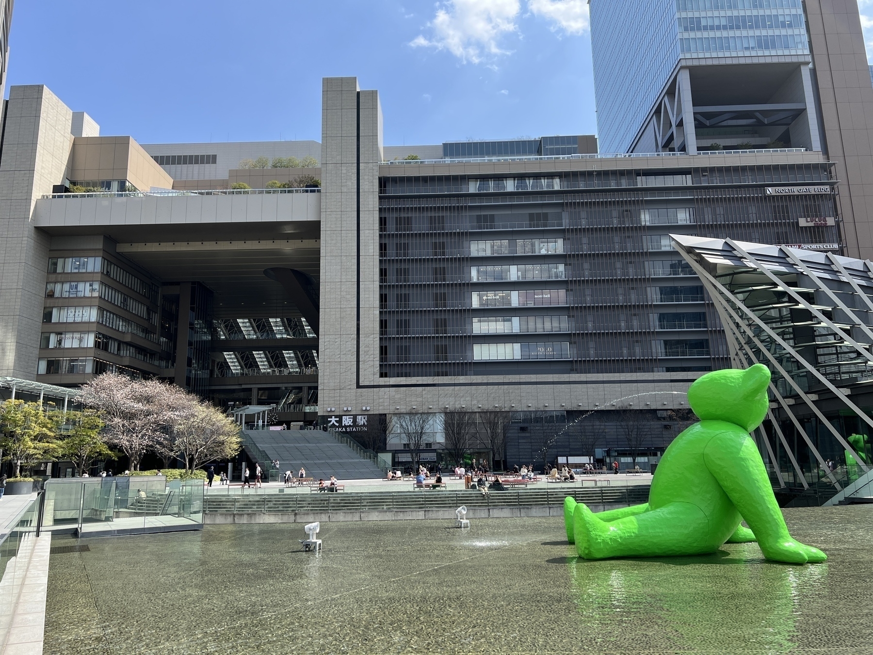 The green Teddy Bear fountain called Ted Hyber, a sculpture by Fabrice Hybert. In background is the Osaka Station Building