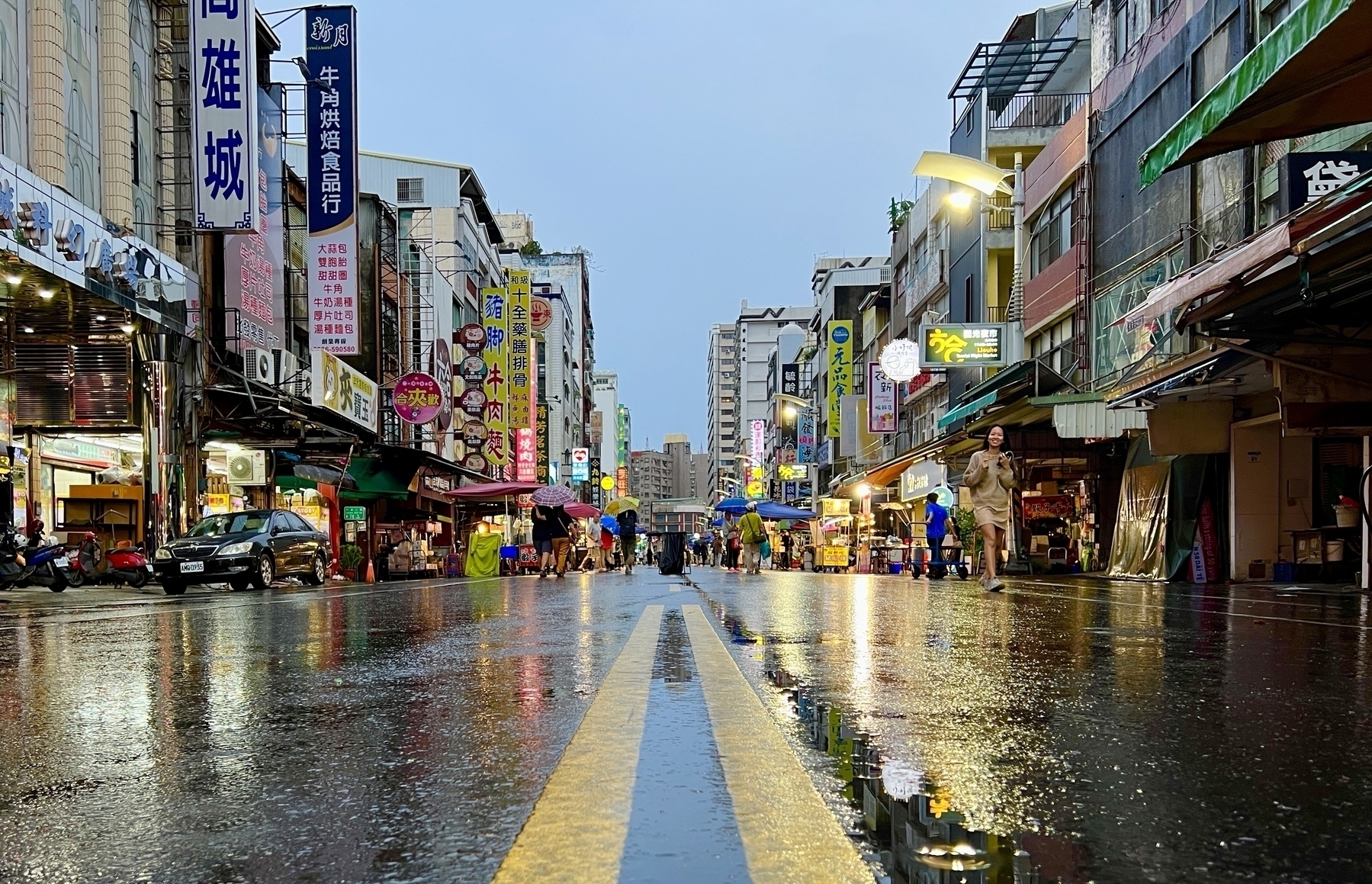 Low shot of a wet street in Kaohsiung. A few street carts are setting up on the edges