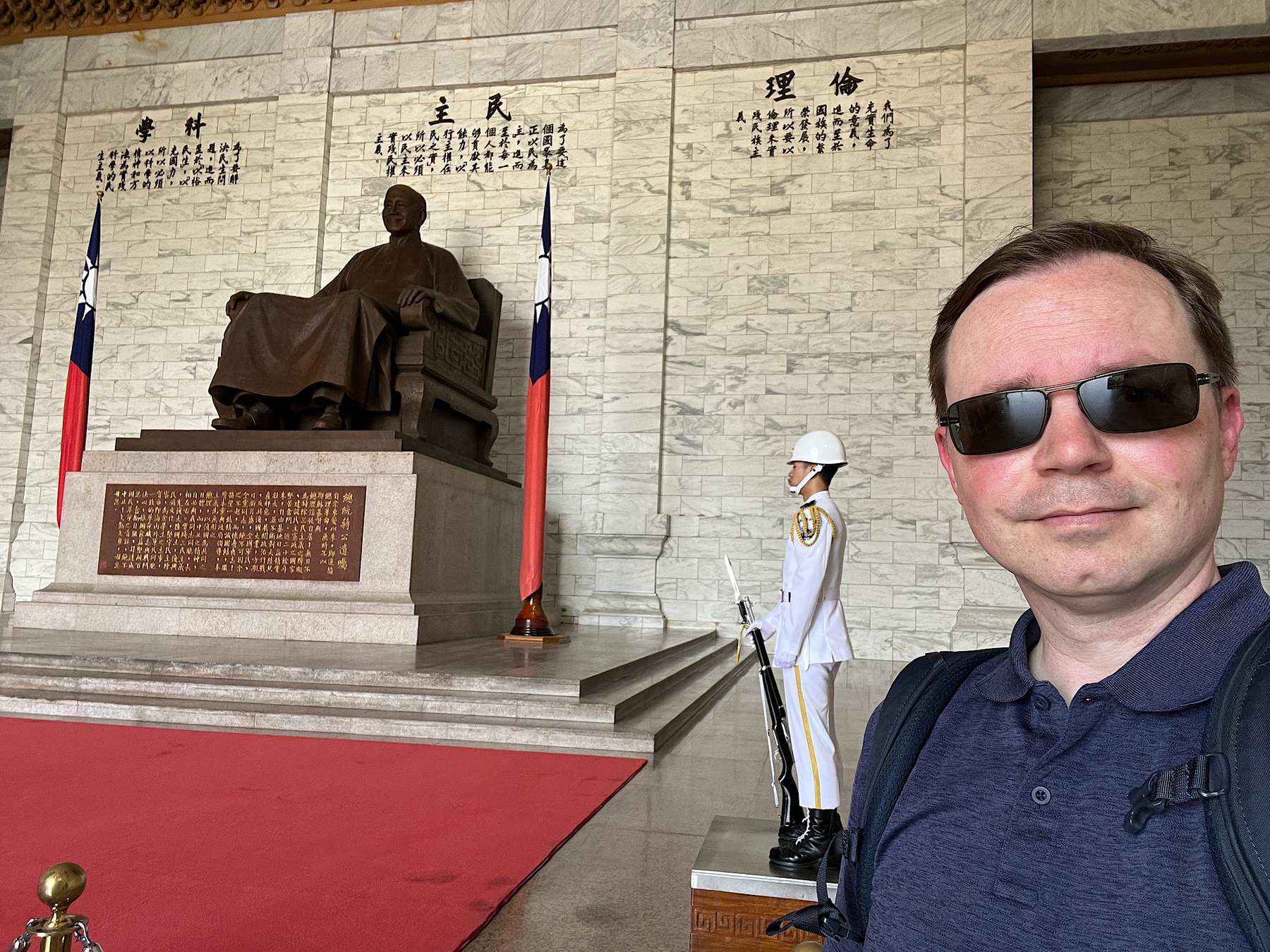 Chad selfie with the seated statue of Chiang Kai Shek and a guard in all white uniform 