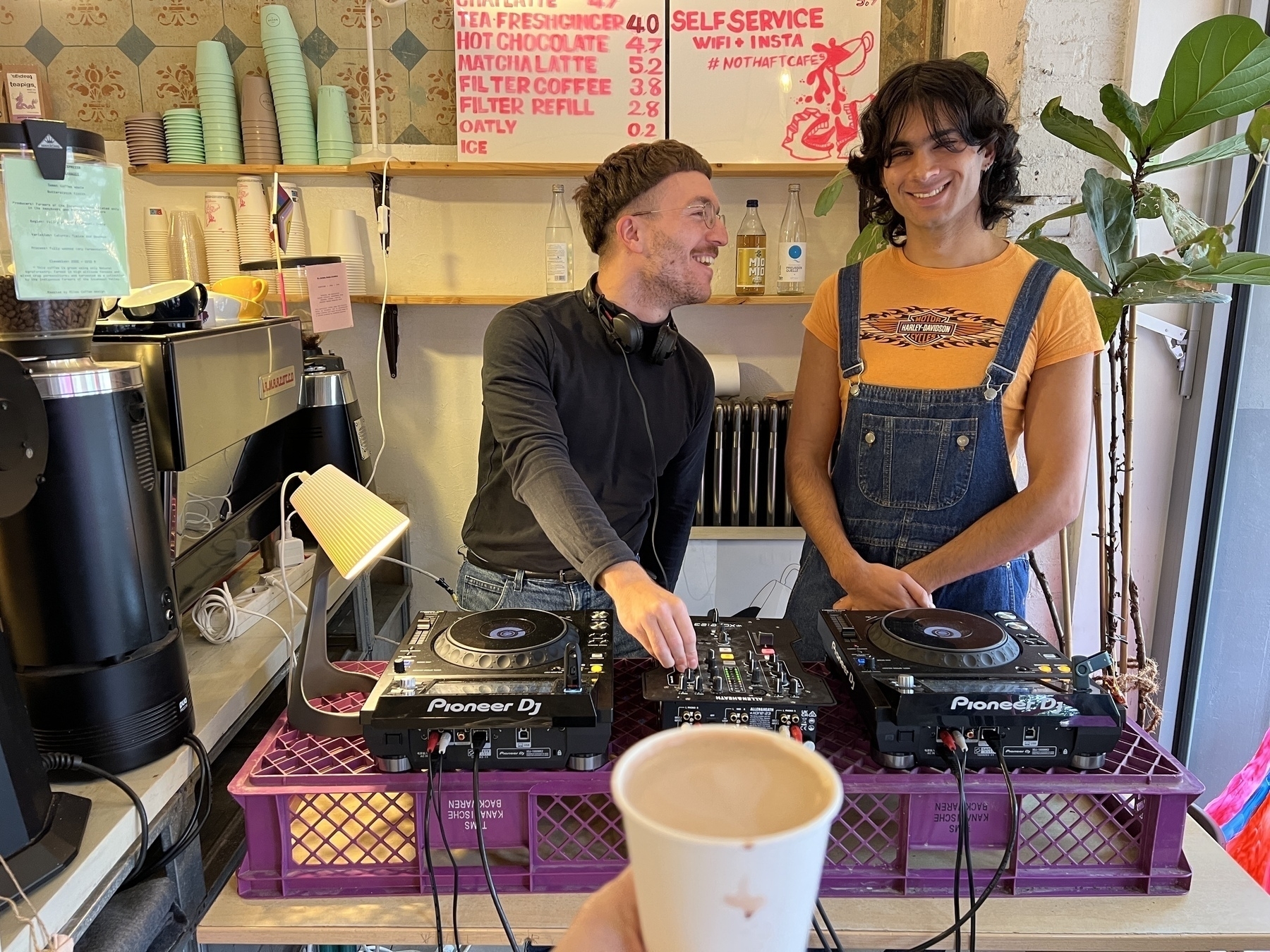 Two DJs spinning the wheels of steel in the corner of a coffee shop