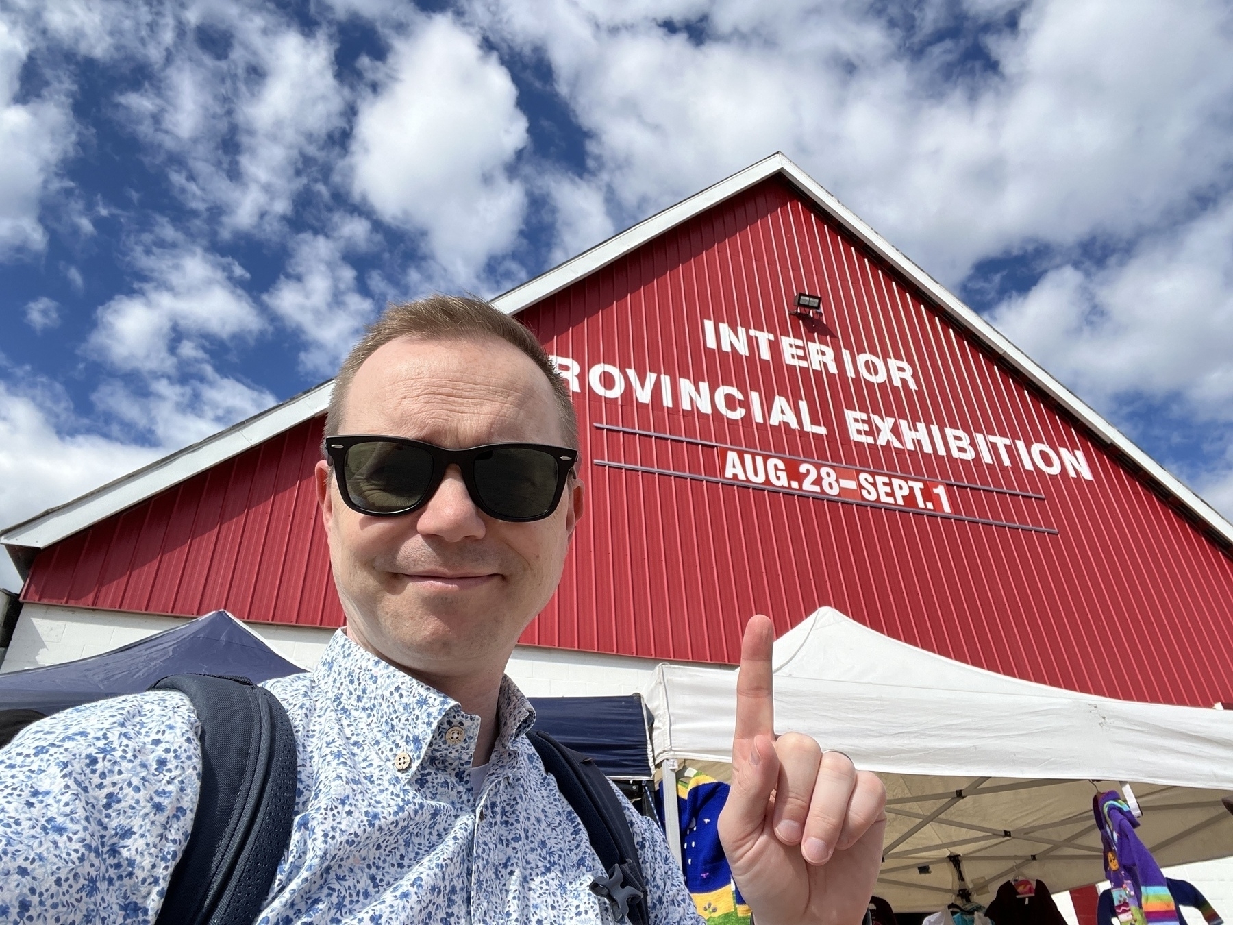 Chad selfie in front of a barn with the sign: Interior Provincial Exhibition, Aug 28 - Sep 1