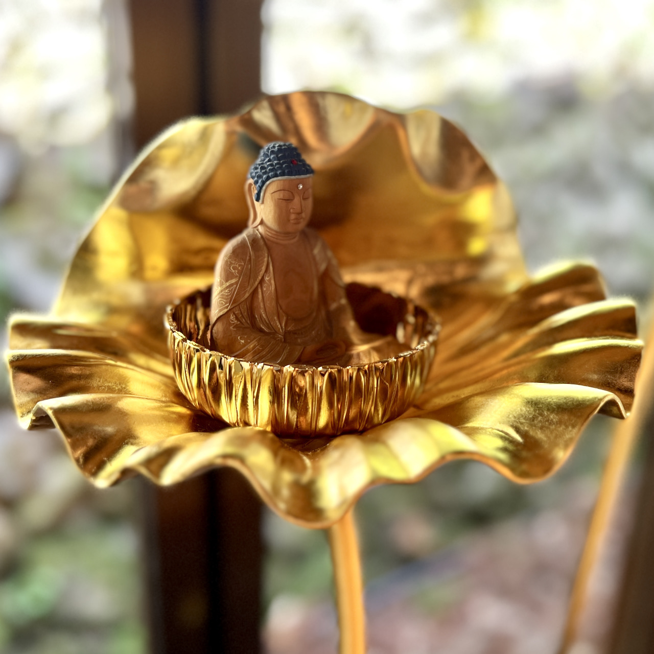 closeup of a Buddha statue rising from a gold lotus leaf