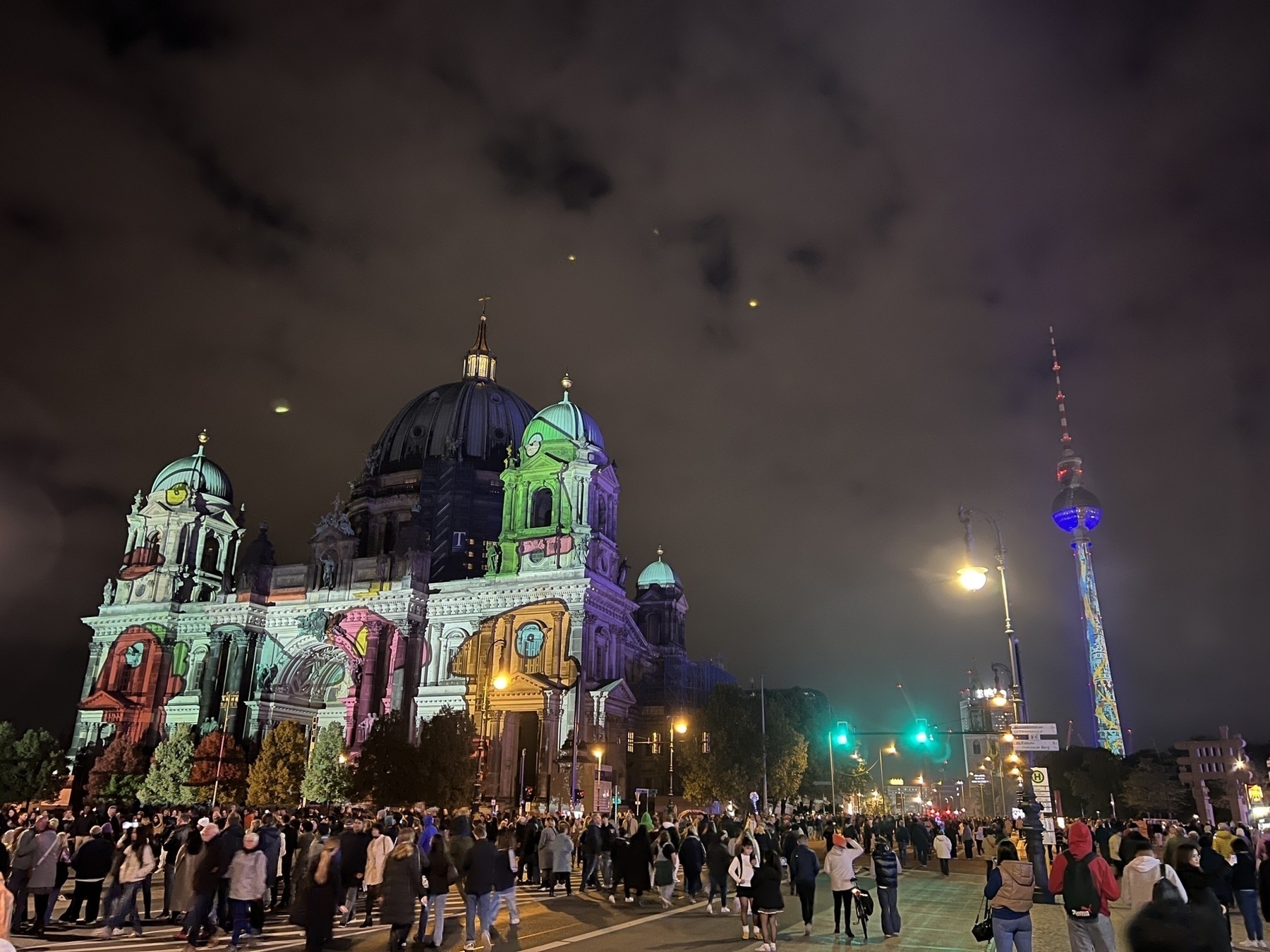 Berlin Dom with a cartoon  being shone on it. The TV Tower in the background