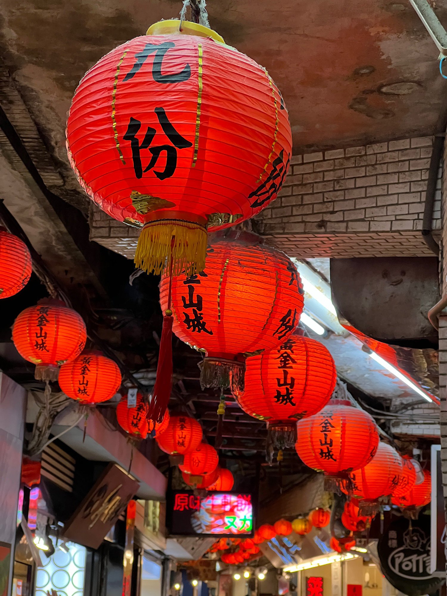 Red lanterns lining the streets above the heads of the (very crowded) Jiufen Old Street shopping area. The lantern in the foreground has the Chinese characters 九份 for Jiufen